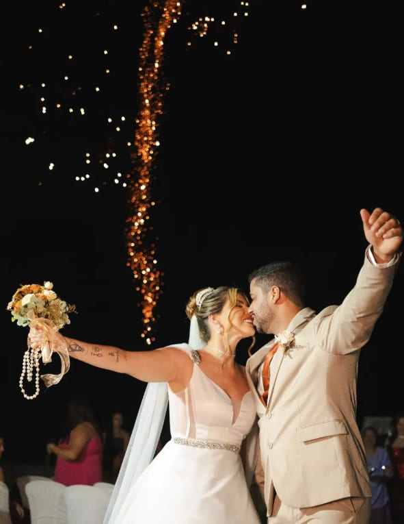 Beijo dos noivos na festa de casamento com luzes ao fundo