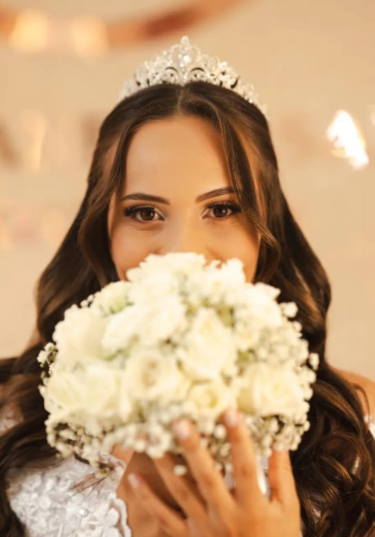 Retrato da noiva com tiara segurando o buquê de rosas brancas